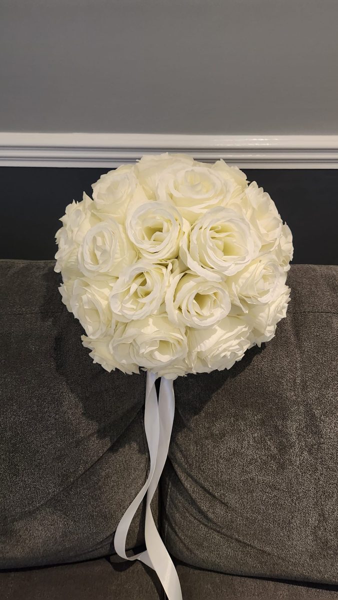 Round posy of cream roses hanging from a white ribbon