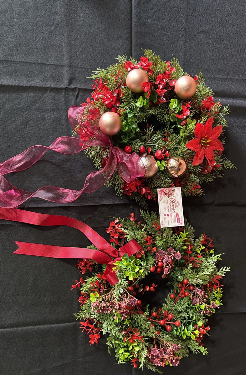 Two small Christmas wreaths with berries, greenery, rose-gold baubles and red ribbon
