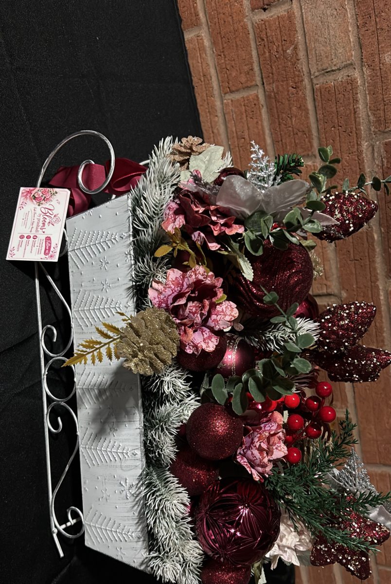 White metal sleigh filled with burgundy baubles, pink blooms, berries and frosted pine